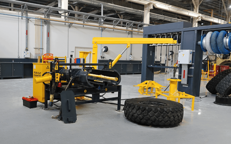 GM Defensive Run-Flat Tire Changing Machine — complete workshop setup with hydraulic press, crane arm, and military run-flat tire